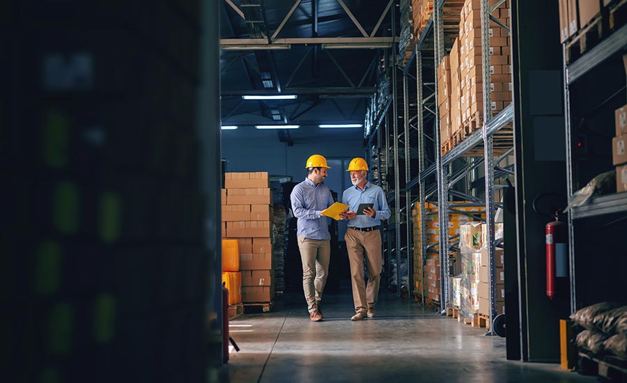 Men wearing hard hats walking in a warehouse​